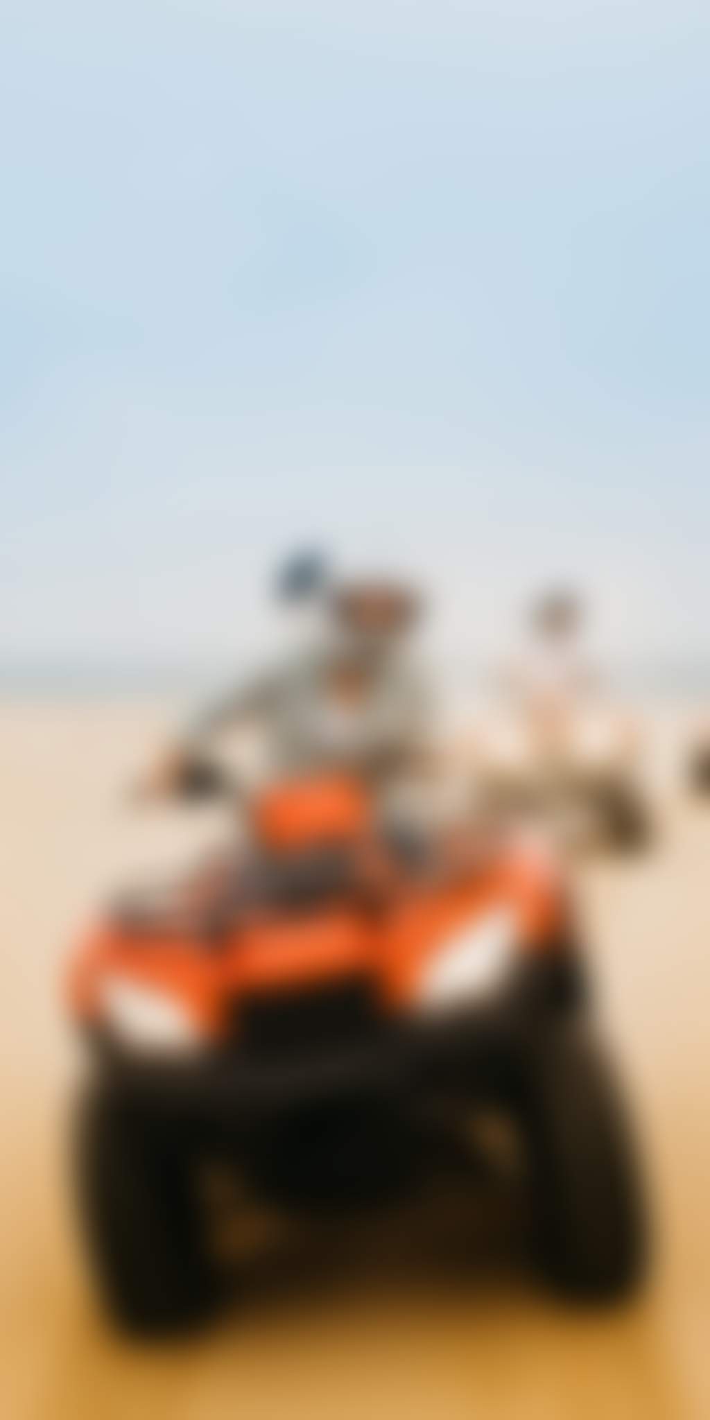 Convoy of three quad bikes rides in a line across sand dunes in port stephens